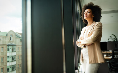 Beautiful african business woman looking outside window in office