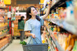 © Timeimage - Young girl is choosing to buy foodstuffs at the supermarket