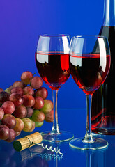 Two glasses of red wine on multicolored background