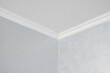 © Volodymyr - White ceiling with a white plinth in a room with gray painted walls. Decoration of the corner between the ceiling and the wall in the room. Ceiling molding in the interior. Detail of corner.