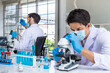 © wirojsid - Two male Asian and Arab researcher scientists working in laboratory, conducting study biohazard substance with scientific equipment and microscope