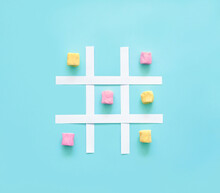 Tic Tac Toe Made Of Pink And Yellow Marshmallows On A Blue Background.
