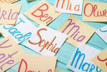 Paper Notes With Different Baby Names On Light Blue Wooden Table