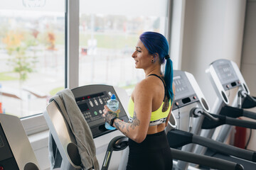 Wall Mural - tattooed young woman running on treadmill