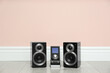 © New Africa - Modern powerful audio speakers and remote on floor near pink wall. Space for text