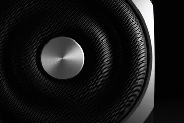 Modern subwoofer on black background, closeup. Powerful audio speaker