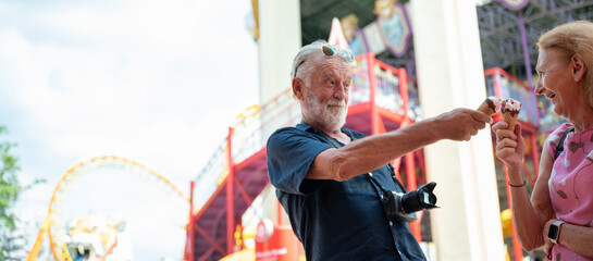 senior old couple celebration for Valentine's Day at Amusement theme park enjoying freedom relaxing, grandmother and grandfather smiling and fun, time to date and married