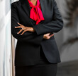 Selective focus of a businesswoman in a classic black suit and red shirt with her arms crossed