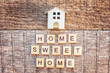 Miniature toy house with inscription HOME SWEET HOME letters word on wooden background. Mortgage property insurance dream home concept. Flat lay top view, copy space
