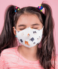 Close-up portrait of a young funny  girl with two ponytails wearing a color mask on pink background. Prevention of coronavirus and covid-19. Photo of funny lady impressed spread covid-19 infection