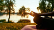 © Svitlana - Cropped shot of a woman doing yoga outdoors near lake or river at sunrise in the morning, sitting in lotus pose on the background of nature