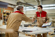 © Drazen - Male workers wearing face masks while shaking hands at carpentry workshop.