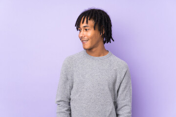 Young african american man isolated on purple background looking side