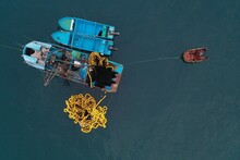 Aerial Top View Of A Small Blue Colored Fishing Boat With A Fishingnet Floating Alongside