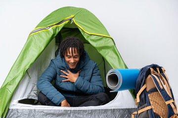 Sticker - Young african american man inside a camping green tent smiling a lot