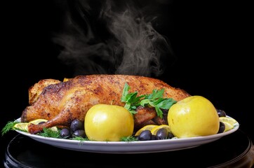 Roast duck with apples, lemon, olives and herbs on a black background