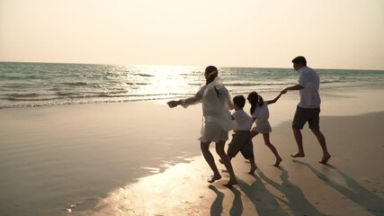 Wall Mural - Happy Asian family on summer holiday vacation. Parents with little child boy and girl running and playing together on tropical beach at summer sunset. Family enjoy and having fun with outdoor activity