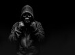 © breakermaximus - Horror photo of a scary man in hoodie with skull face on black background.