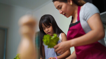 Happy Asian family stay home. Beautiful mother with cute little daughter and son preparing homemade sandwich with cheese in the kitchen. Mom with kids enjoy and having fun cooking breakfast together.