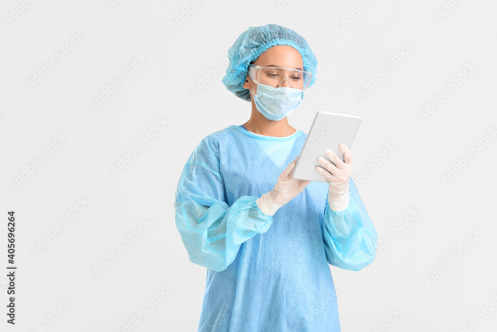 Portrait of female surgeon with tablet computer on light background