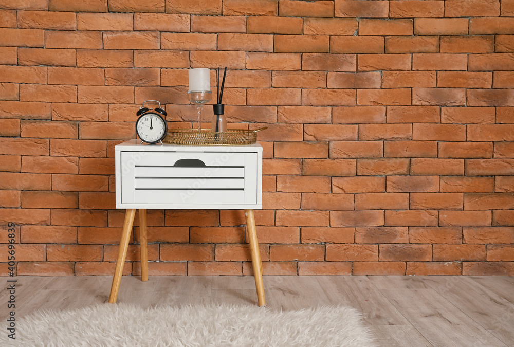 Alarm clock and decor on table near brick wall