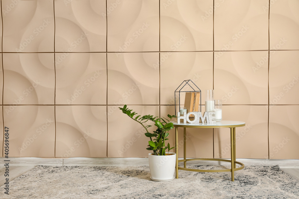Table with books, decor and houseplant near color wall