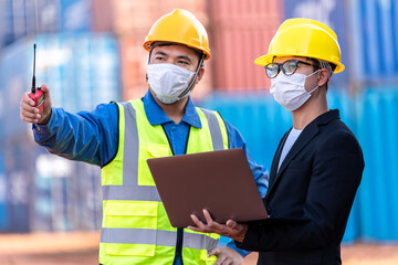 Asian male logistic warehouse foreman with worker using laptop checking list planning and strategy of container boxes from cargo freight ship. industry import export shipping business.