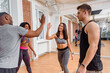 Group of multiethnic happy friends giving high five in modern gym after training