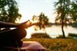 © Svitlana - Unity with nature. Cropped shot of a woman doing yoga outdoors near lake or river at sunset, sitting in lotus pose and meditating on the background of nature