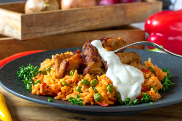 Stir-fried pork meat with serbian djuvec rice on a dark plate