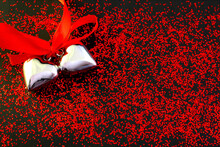 Two Silver Hearts Are Tied With A Red Ribbon And Lie On A Black Background With Red Glitter
