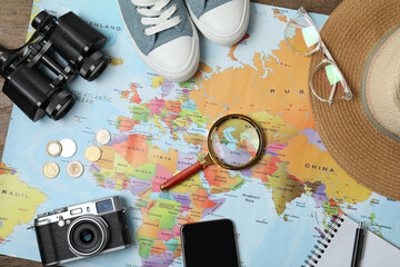 Wall Mural - Flat lay composition with world map and different travel accessories on wooden table. Planning summer vacation trip