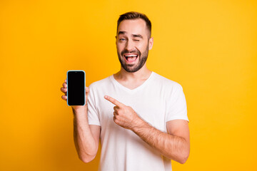 portrait of attractive cheerful guy holding in hand demonstrating device winking isolated over brigh
