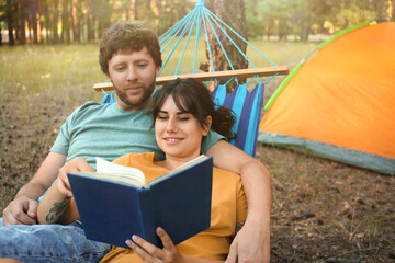 Wall Mural - Lovely couple with book resting in comfortable hammock outdoors