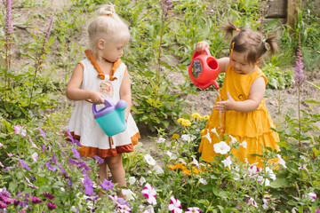 Two little girls sisters watering flowers