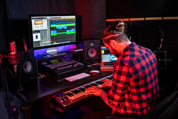 Canvas Print - Hipster man with beard in headphone is playing keyboard and sining his new song in stereo studio to record brand-new track .