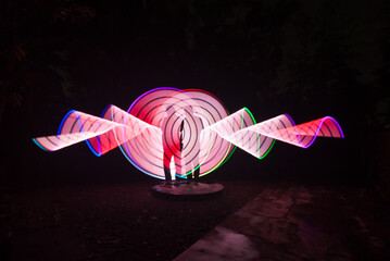 Two person standing against beautiful red and white circle light painting as the backdrop