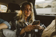 © Criene Images - young caucasian woman using smartphone sitting in backseat of car