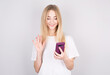 © MP Studio - Photo of cheerful cute beautiful young woman holding up a video call by mobile phone isolated over white wall. Looking towards Copyspace.