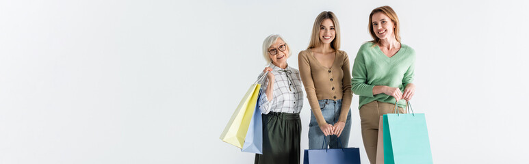 Wall Mural - three generation of happy women holding shopping bags isolated on white, banner