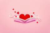 Fototapeta Mapy - Red heart with medical protection mask on light pink background