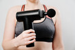 © Maria - woman holds massage gun. medical-sports device helps to reduce muscle pain after training, helps to relieve fatigue, affects problem areas of body, improves condition of skin.