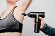 © Maria - woman uses massage gun. medical-sports device helps to reduce muscle pain after training, helps to relieve fatigue, affects problem areas of body, improves condition of skin.