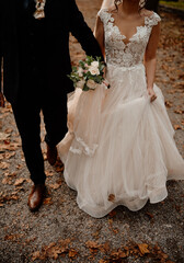 Canvas Print - Vertical shot of a groom and a bride walking in a park