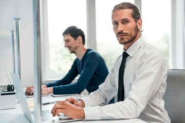 Wall Mural - serious business man sitting at an office Desk and looking at you