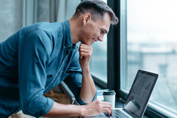 man with a laptop standing near the window .