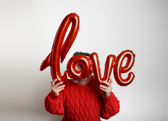 Poster - Male holding a balloon with the word love on white background.Valentine's Day