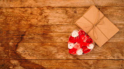 Letters in craft paper envelopes and a gift of roses on a wooden background - Top view