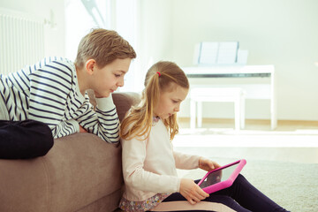 Wall Mural - Happy siblings children playing with tablet on floor at home