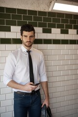 Canvas Print - Handsome young man holding mobilephone, standing at underground station.